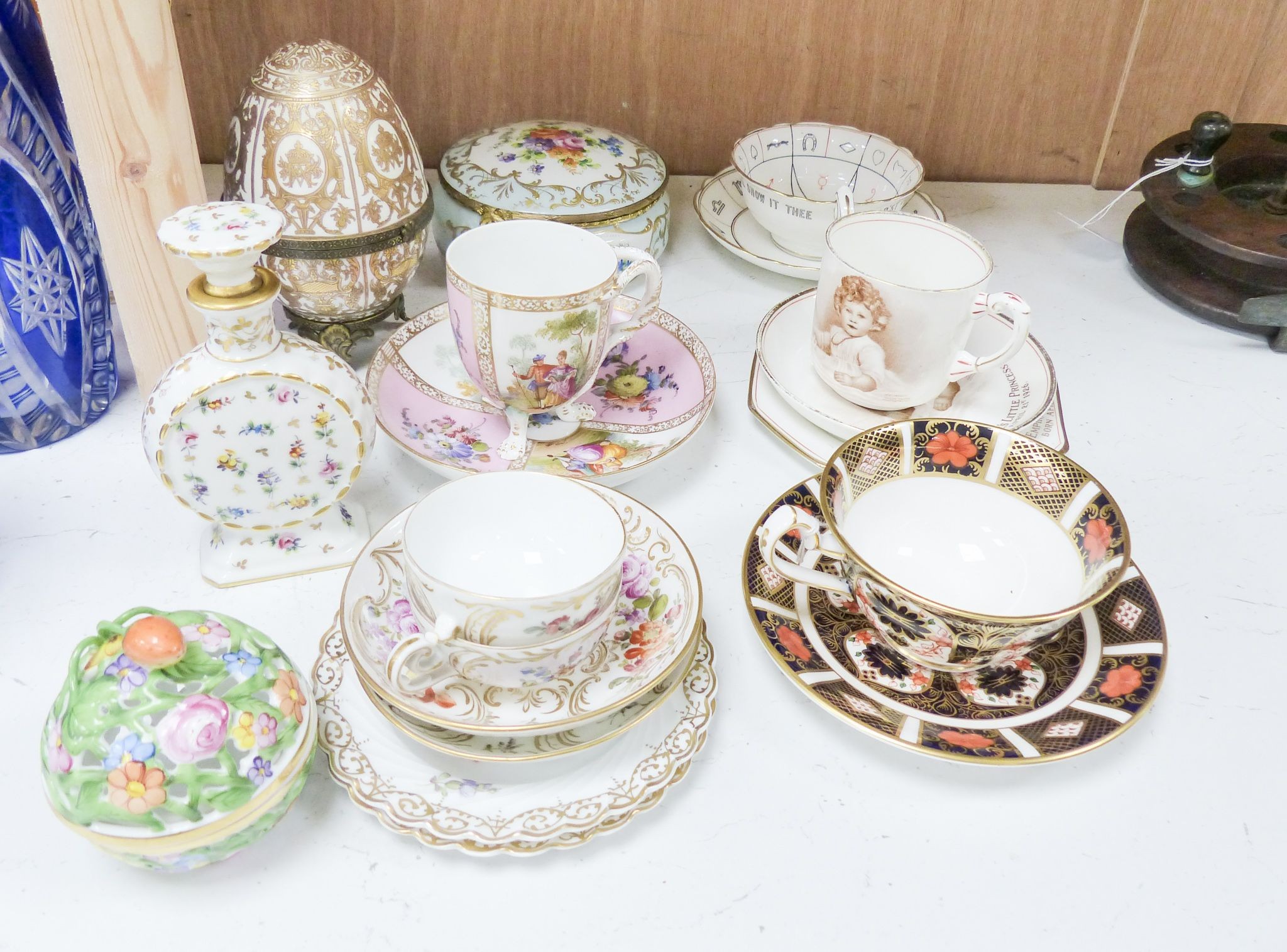 A group of Dresden and Continental porcelain cups and saucers boxes and covers and a scent bottle, 14 cm high